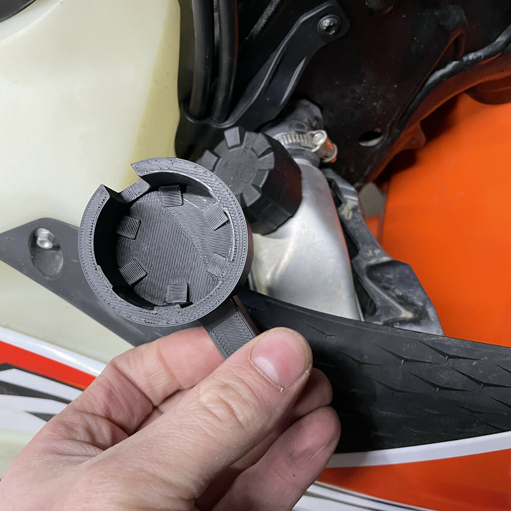 Close-up of a hand holding a black rubber gasket against a motorcycle.