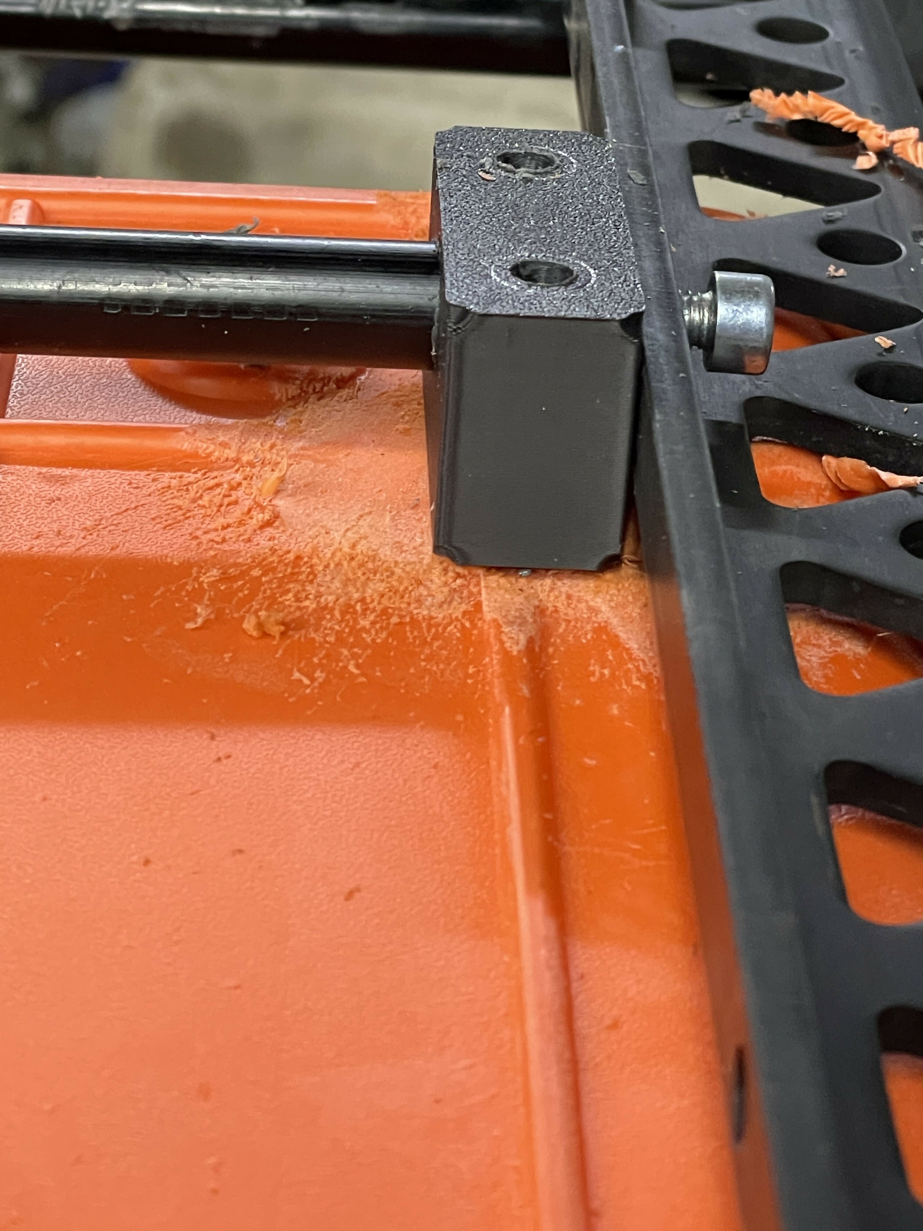 Close-up of a black metal bracket attached to an orange surface
