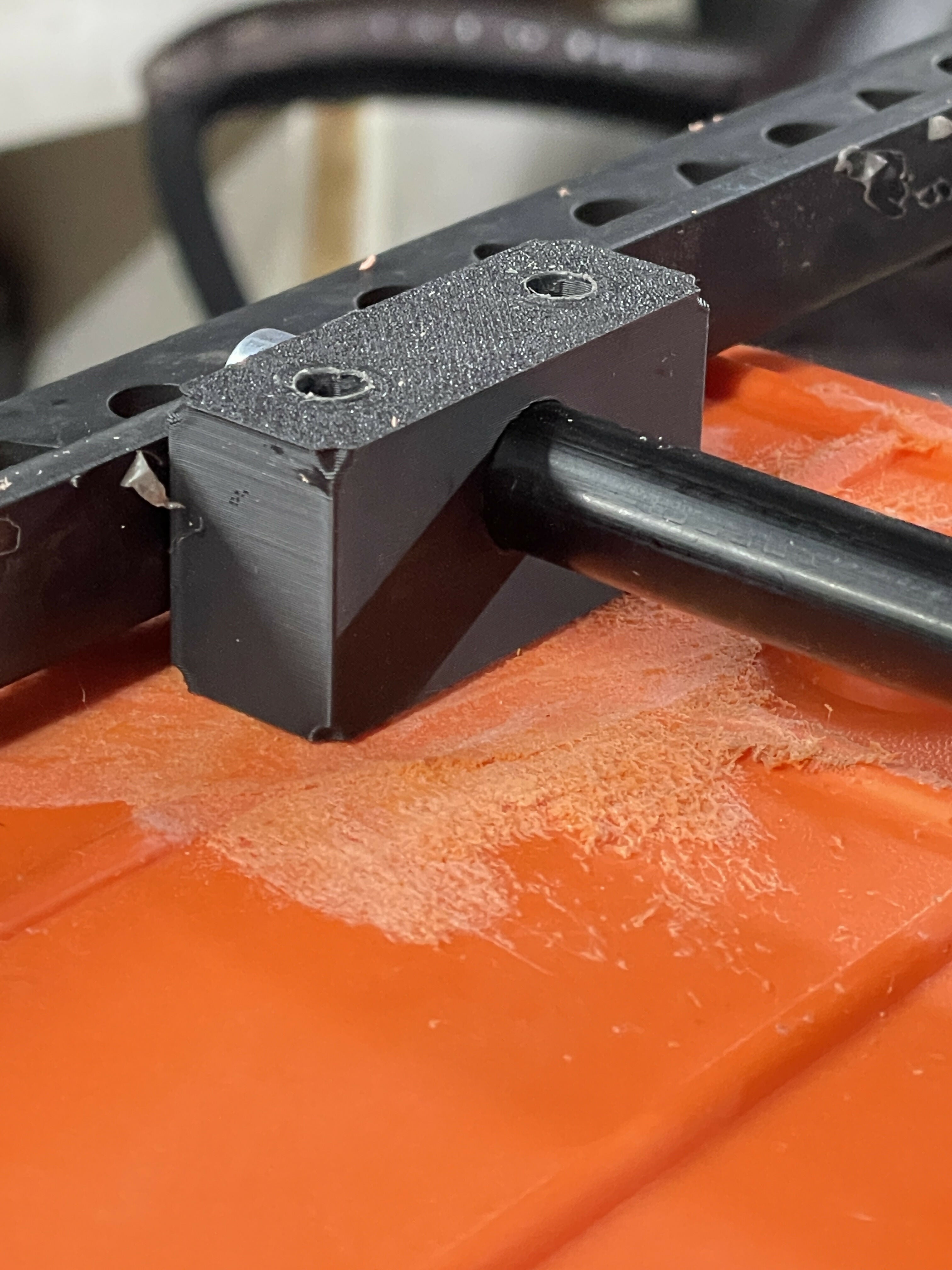 Close-up of a black metal bracket on an orange surface